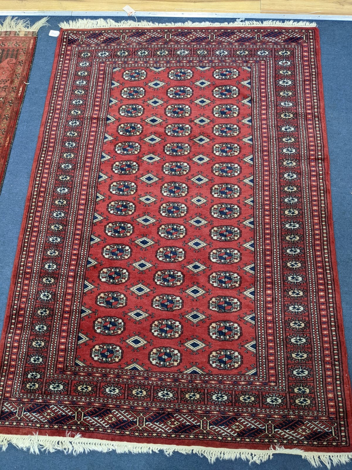 A Bokhara red ground rug, 180 x 126cm and two other rugs